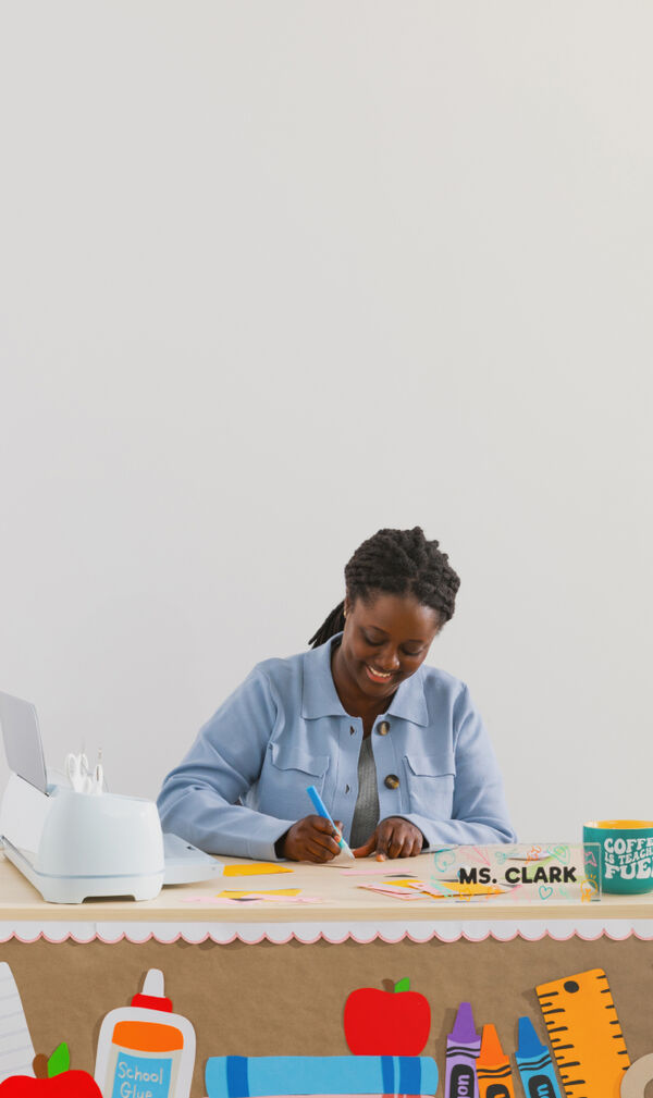 Teacher sitting at her desk using a Cricut Maker 3 machine